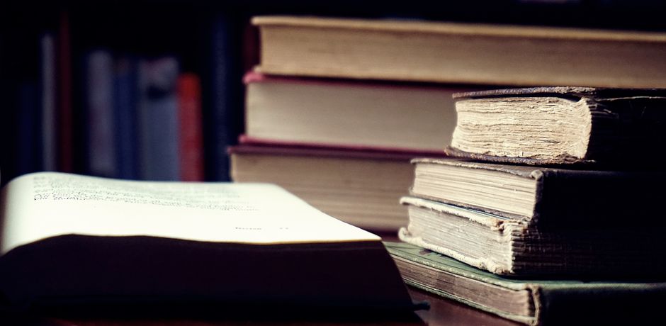 Bookshelf with various books in a well-lit home office, warm ambiance.