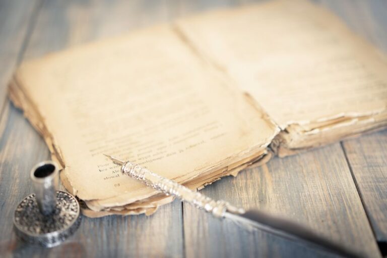 Close-up of an antique book and vintage pen on a rustic wooden table, evoking a sense of history and nostalgia.