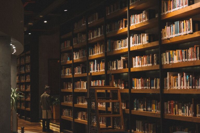 A quiet library with a man standing, surrounded by book-filled wooden shelves.