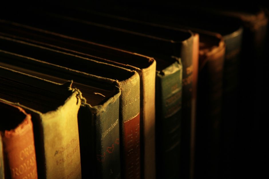 Close-up of an antique book and vintage pen on a rustic wooden table, evoking a sense of history and nostalgia.